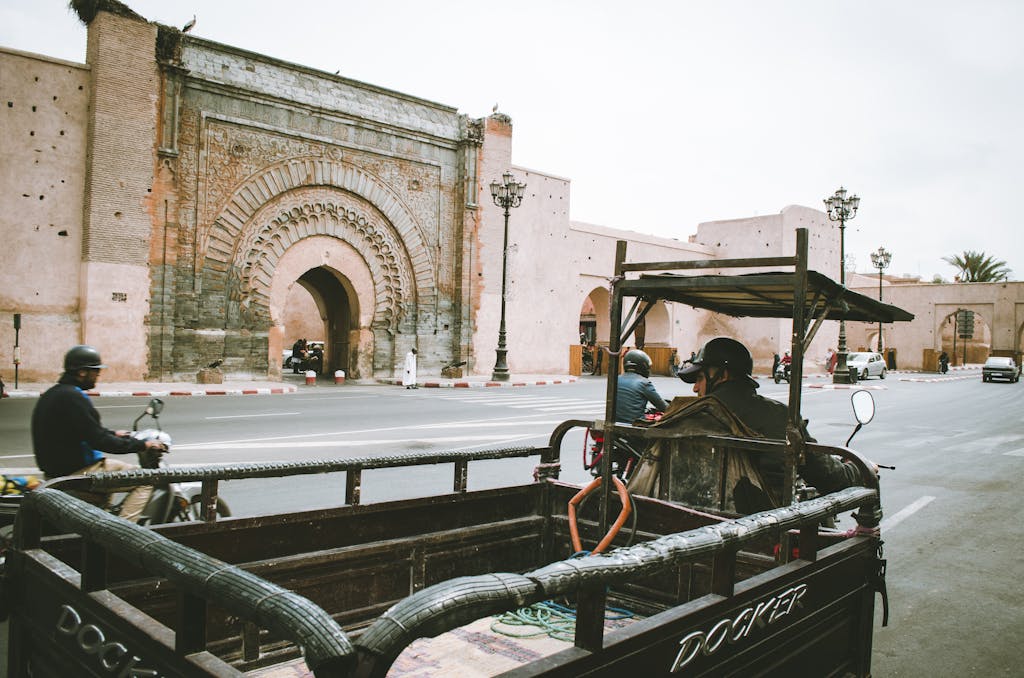 17 Enchanting Destinations in Morocco That You Must Experience 3 A bustling city street with motorbikes and cars near an ornate historical gate.