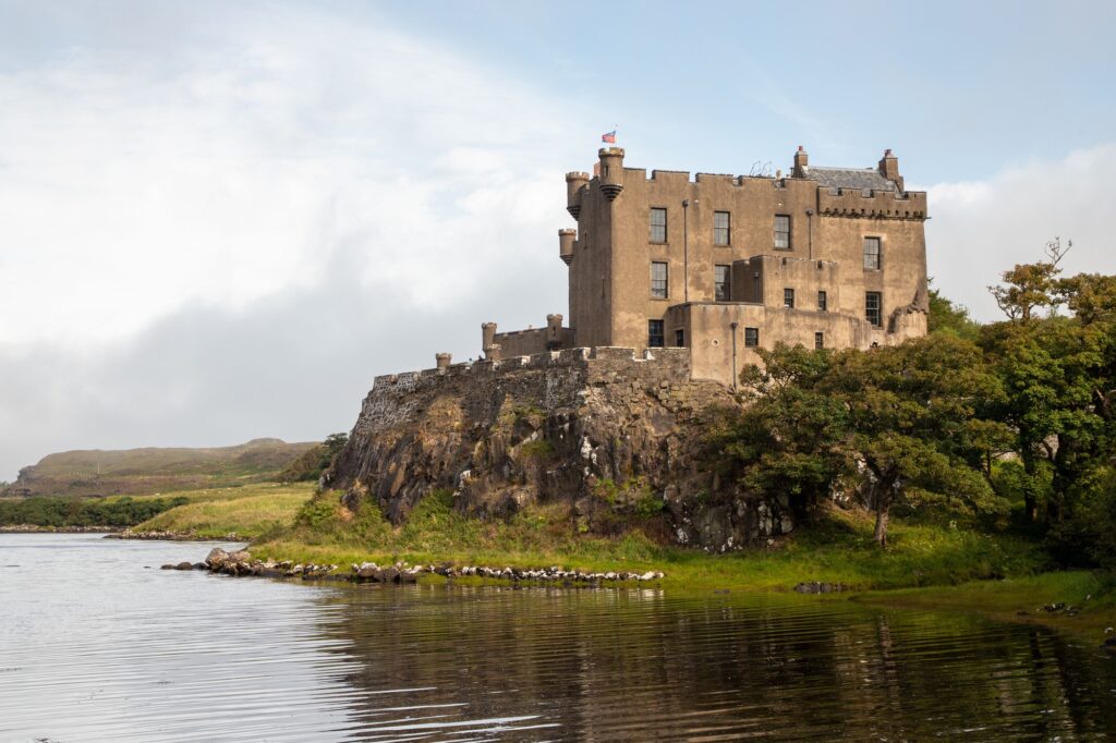 21 Enchanting Castles in Scotland You Must Explore 13 Closeup of the Dunvegan Castle on a rocky cliff on the bank of a river in Scotland