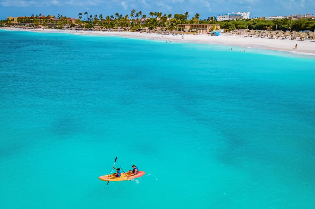 10 Unforgettable Party Islands You Need to Experience 4 Couple Kayaking in the Ocean on Vacation Aruba Caribbean sea, man and woman mid age kayak in ocean