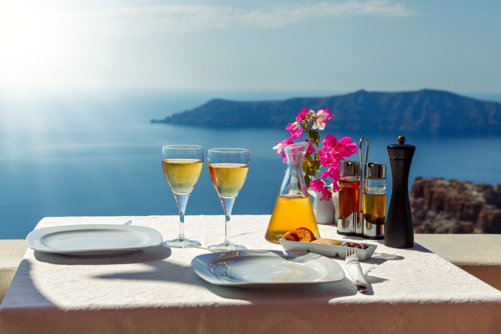 15 Extraordinary Sea Cliffs You Can’t Miss on Your Travels 8 Table and two glasses of wine the island of Santorin