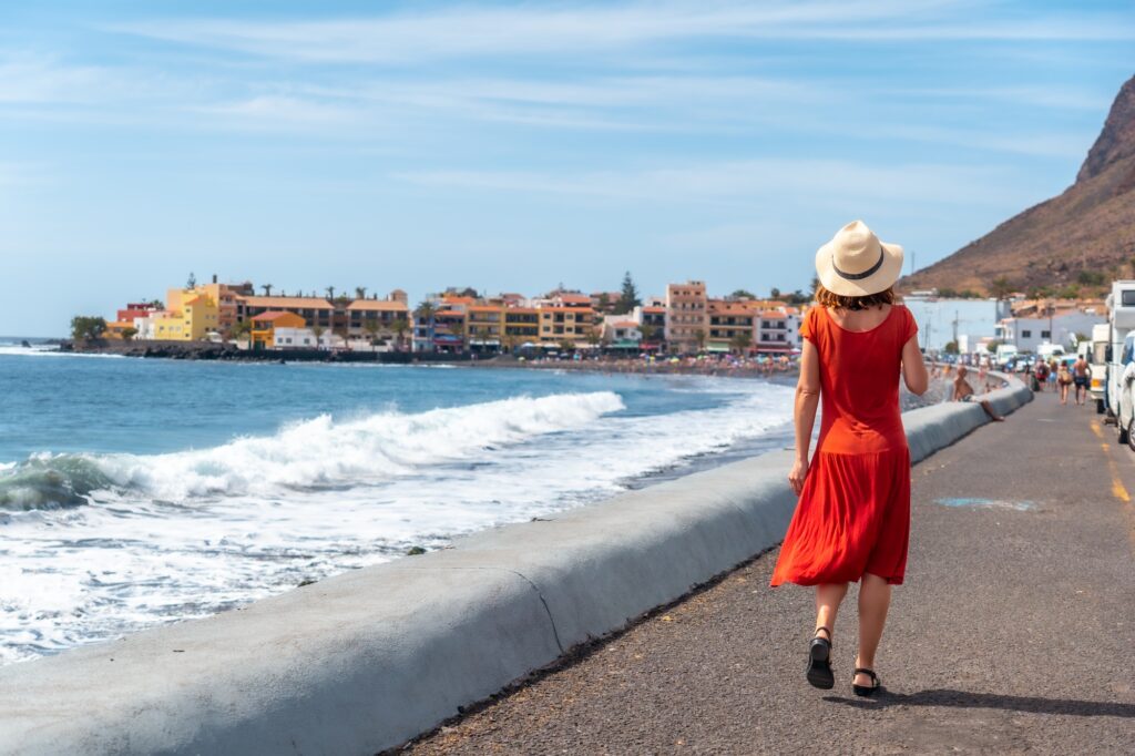 10 Enchanting Beaches in the Canary Islands You Cannot Miss 11 A tourist walking along the promenade on the beach of Valle Gran Rey in La Gomera, Canary Islands