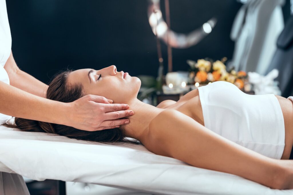 Beautiful young woman having reiki healing treatment in health spa center