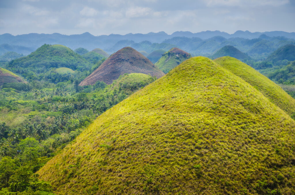 10 Enchanting Tourist Attractions in the Philippines You Can't Miss 10 Chocolate hills in Bohol, some Clouds in Background, Philippines