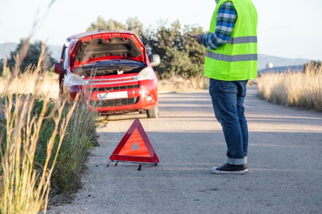 5 Compelling Reasons You Shouldn't Travel Without Insurance 4 Relaxed man texting a mechanic because his car broke down in the middle of the road.